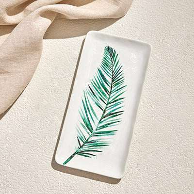 RAINFOREST PORCELAIN PLATE - LA delicate porcelain plate with a smooth, glossy surface. The plate features a minimalist design, with a vibrant green leaf positioned in the center. The leaf is finPorcelain Plate