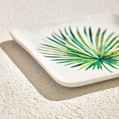 RAINFOREST PORCELAIN PLATE - SA delicate porcelain plate with a smooth, glossy surface. The plate features a minimalist design, with a vibrant green leaf positioned in the center. The leaf is finPorcelain Plate