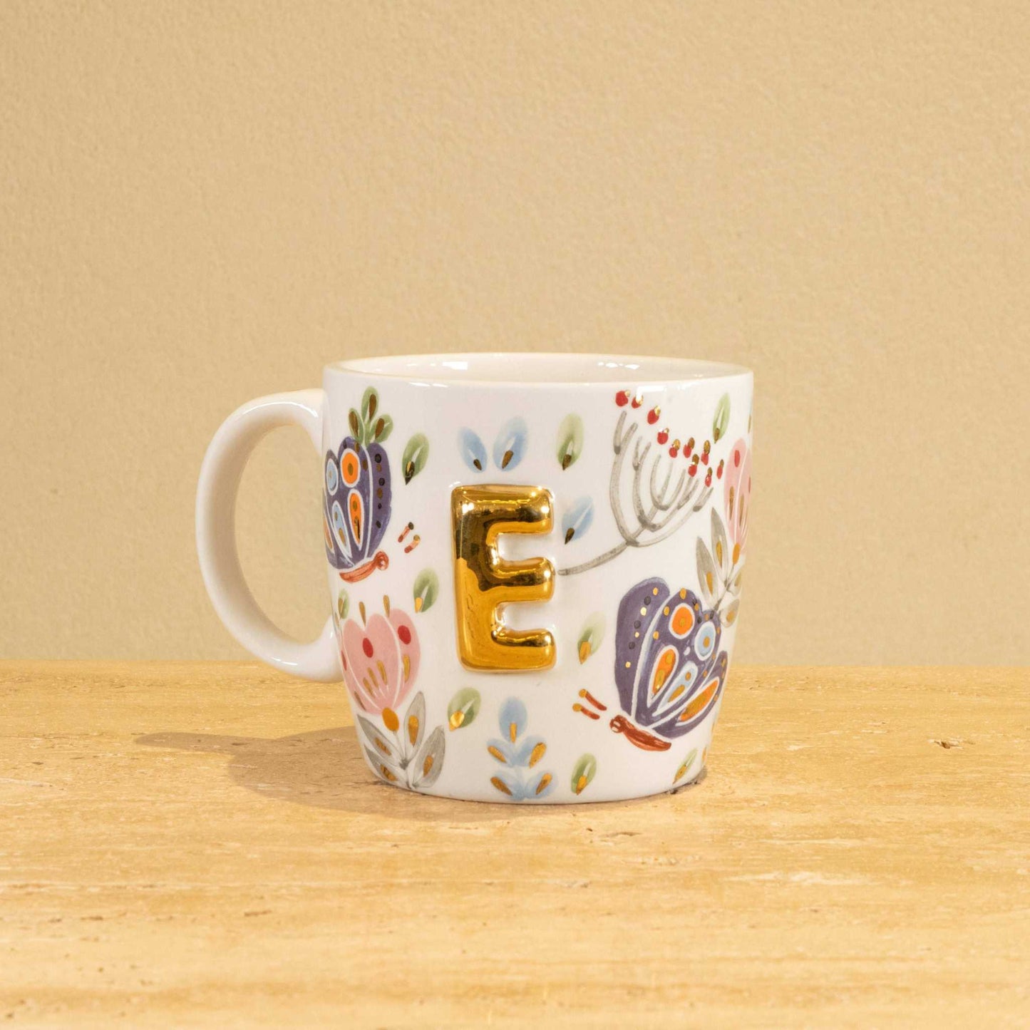 Personalized handmade ceramic mug with gold-plated letter "E" and floral design.