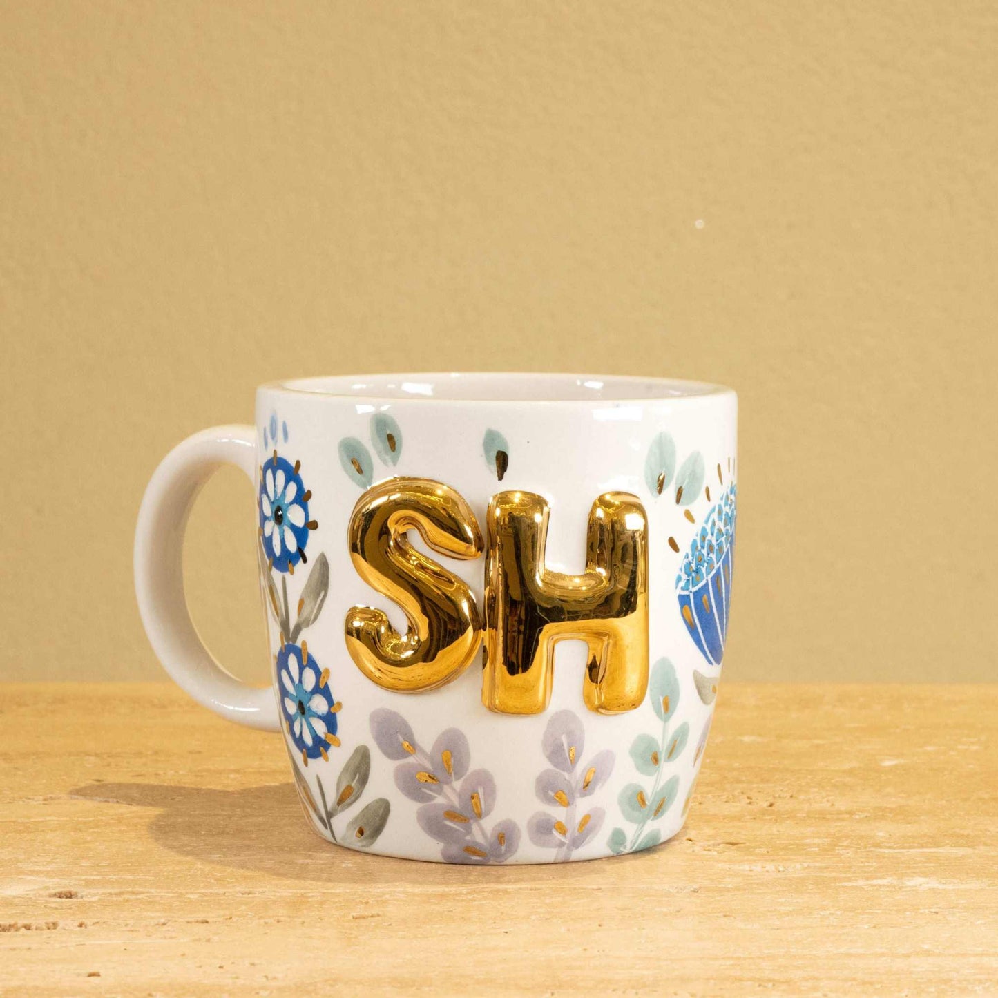 Personalized handmade ceramic mug with gold-plated "SH" letters and floral design.