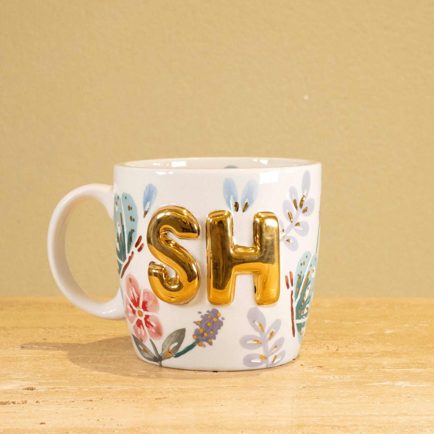 Personalized handmade ceramic mug with gold-plated 'SH' and floral design.