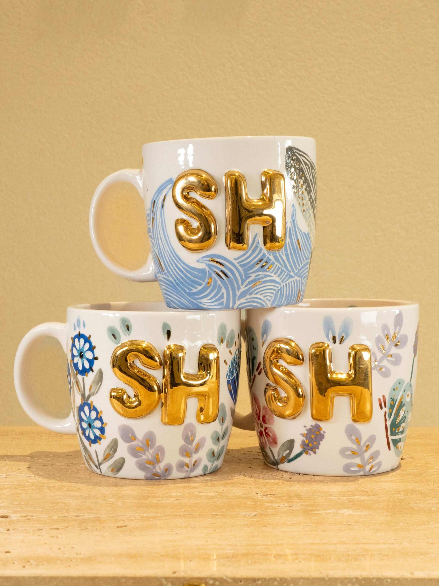 Personalized handmade ceramic mug with gold-plated "SH" letters and floral design.
