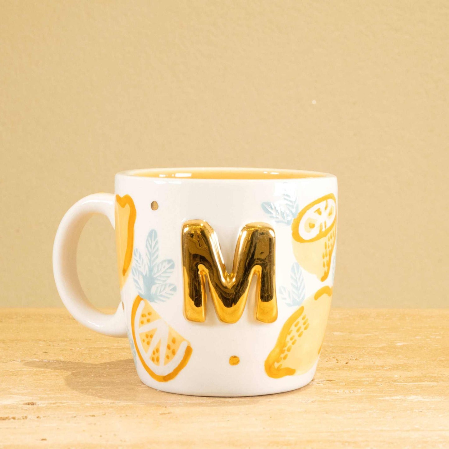 Personalized handmade ceramic mug with gold-plated letter "M" and unique floral design.