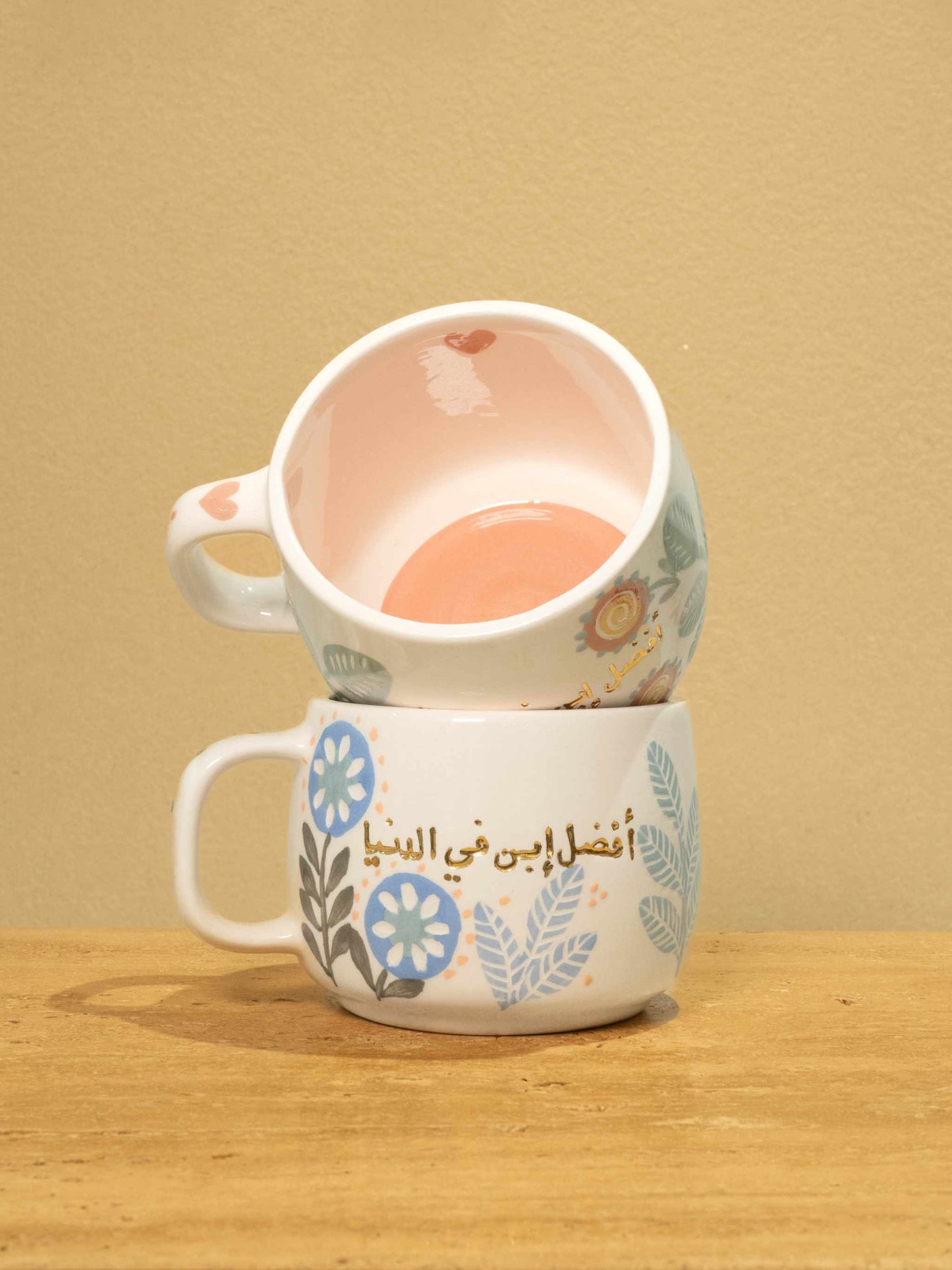 Handmade ceramic mug with gold-plated Arabic text "Best Son in the World" and floral design.