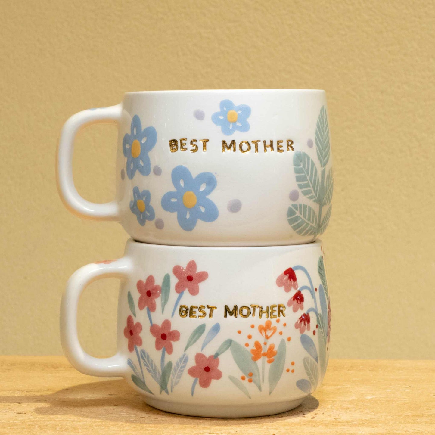 Personalized ceramic mug with gold "BEST MOTHER" and floral design.