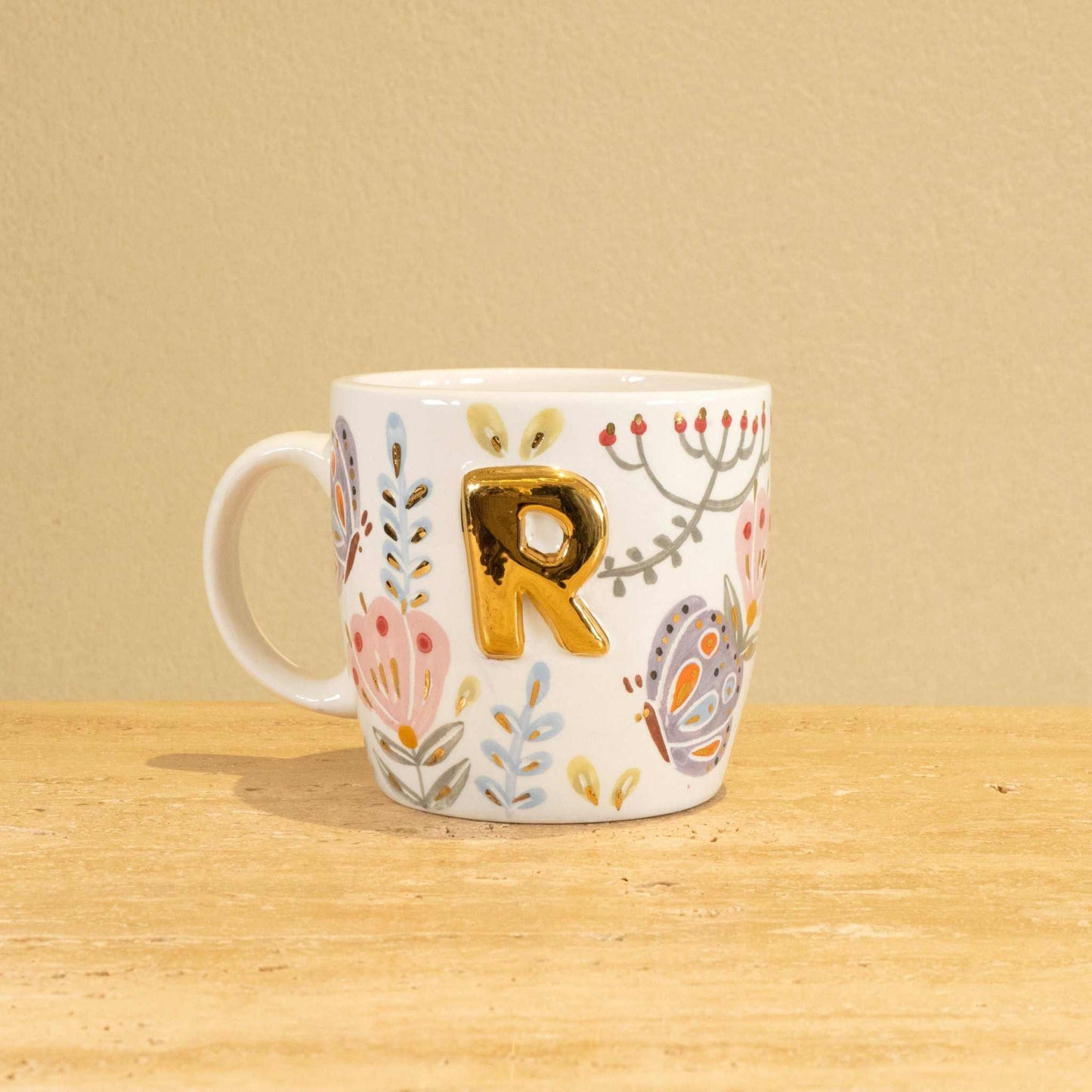 Custom handmade ceramic mug with gold-plated initial "R" and floral design.