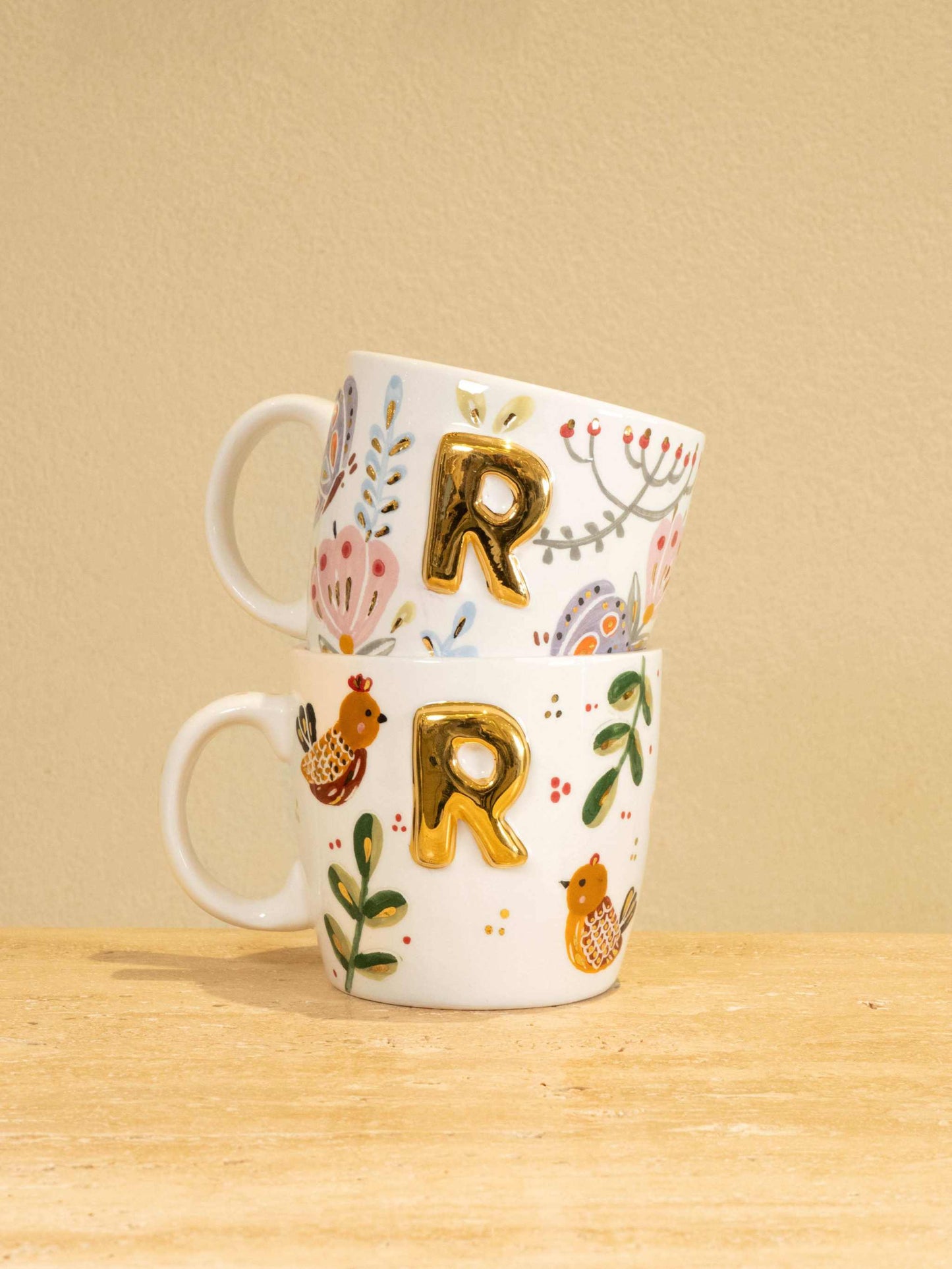 Custom handmade ceramic mug with gold-plated initial "R" and floral design.