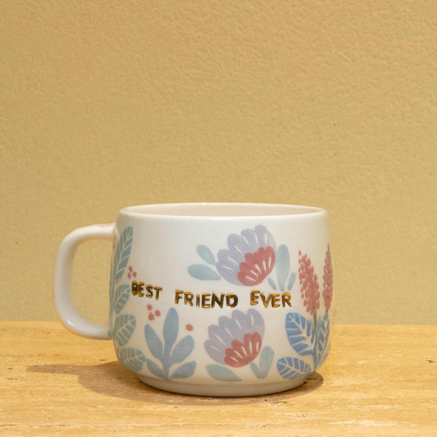 Handmade ceramic mug with gold "BEST FRIEND EVER" lettering and vibrant floral design.