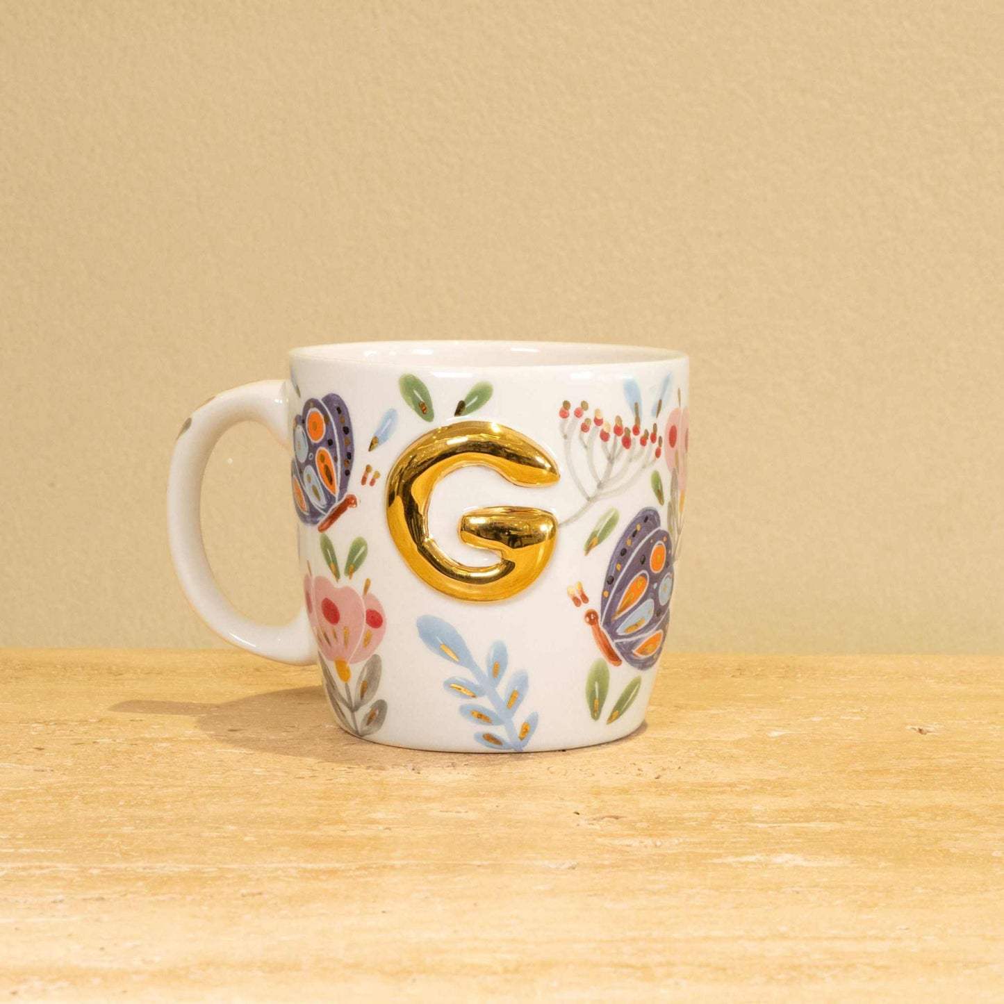 Custom handmade ceramic mug with gold-plated initial "G" and floral design.