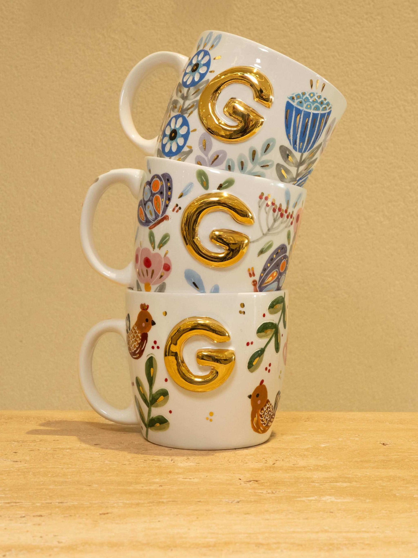Custom handmade ceramic mug with gold-plated initial "G" and floral design.