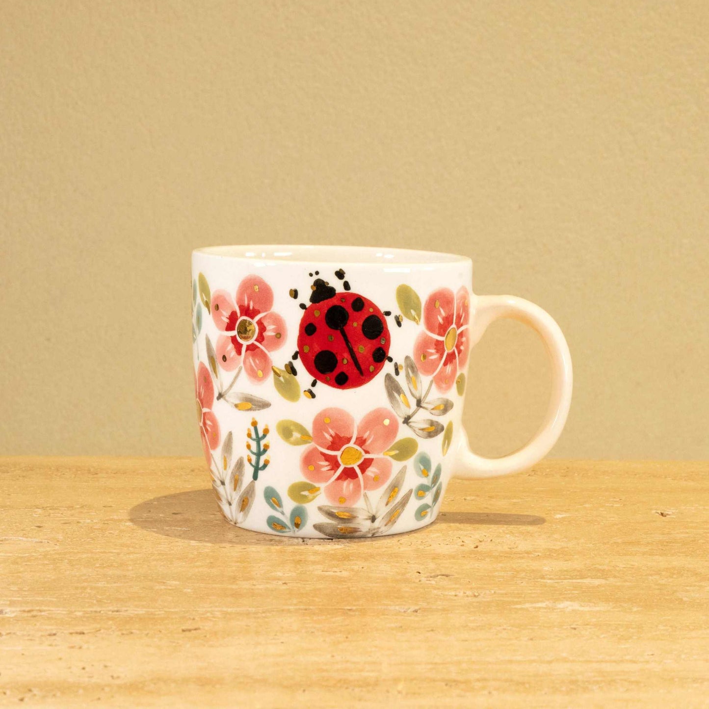Custom handmade ceramic mug with gold-plated initial "V" and floral design.