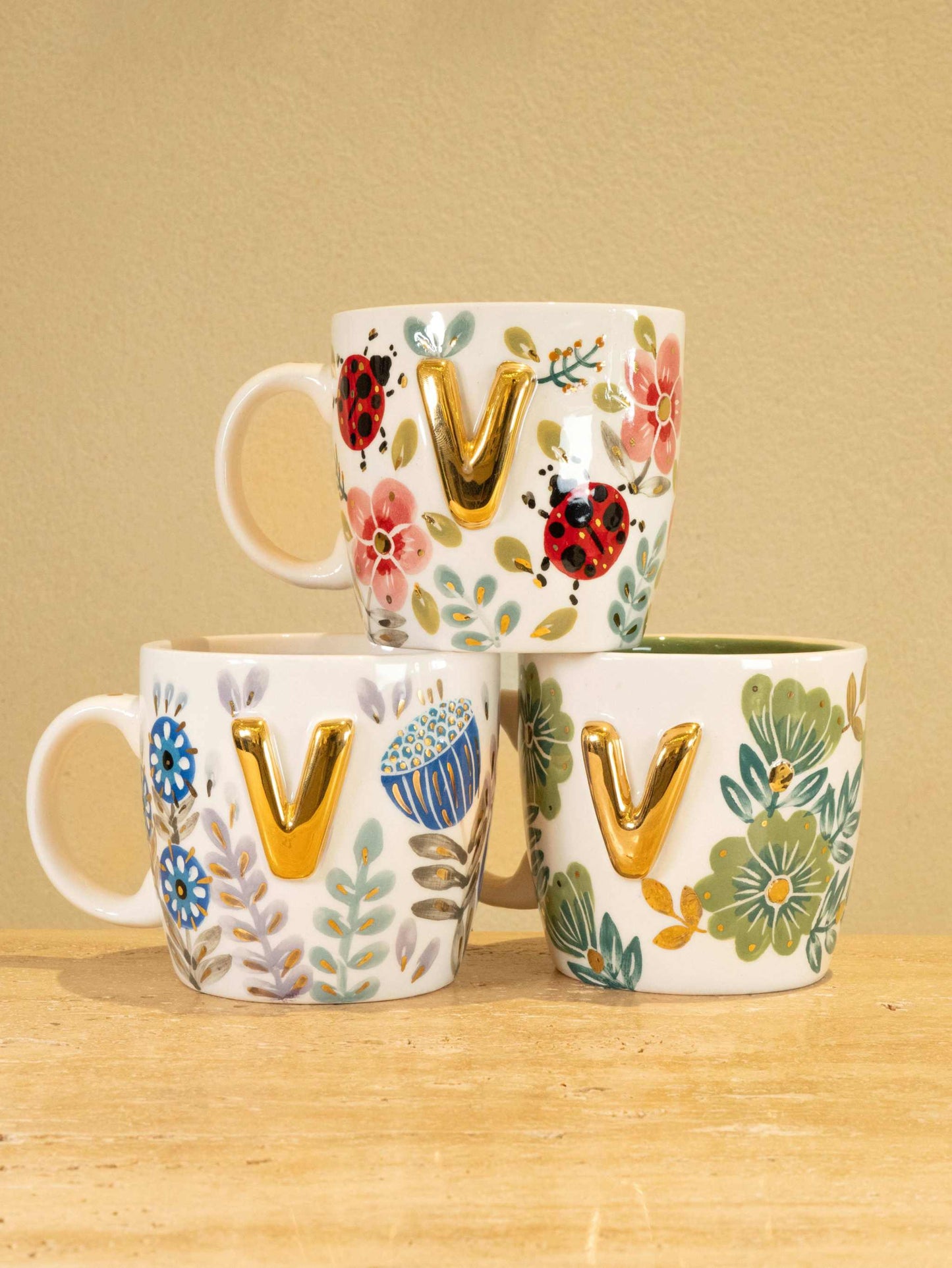 Custom handmade ceramic mug with gold-plated initial "V" and unique floral design.