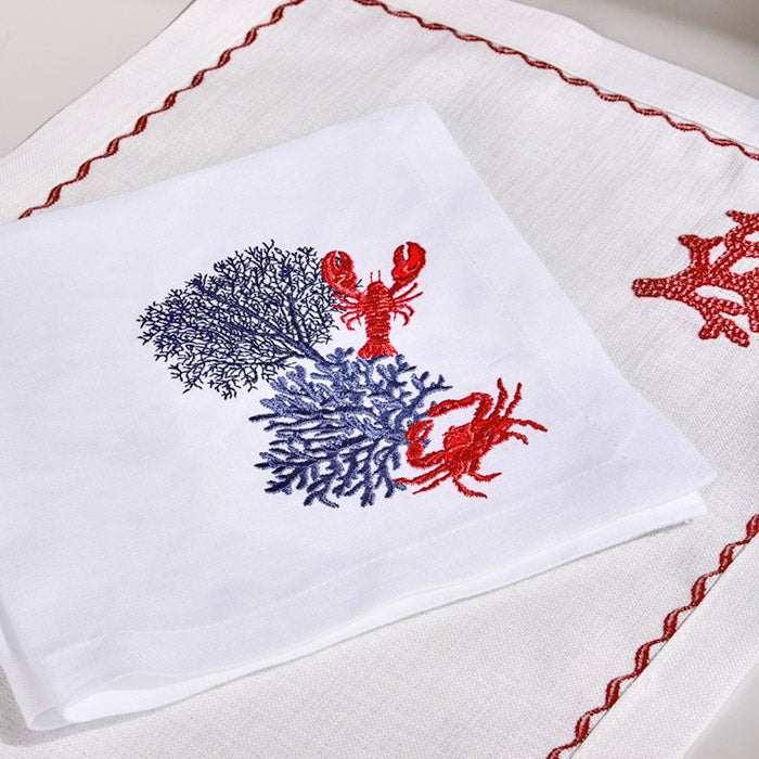 White linen placemat and napkin set with coral crab and lobster navy embroidery.