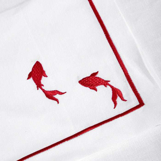 White linen placemat and napkin set with red fish embroidery and picot edging.
