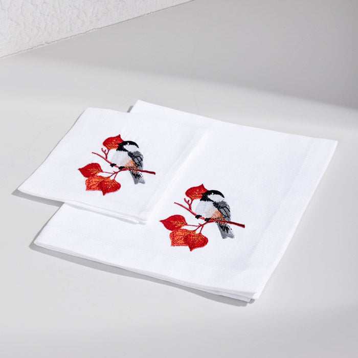 White linen cocktail napkin with embroidered bird and autumn leaves design.