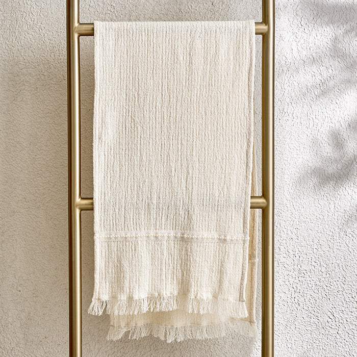 Beige pearl lace table runner with delicate detailing hanging on a gold rail.