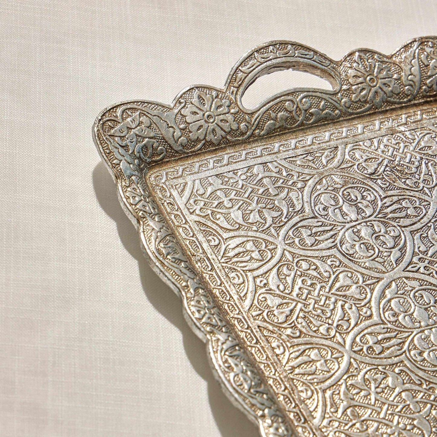 Serving Rectangular Tray with ornate design and curved edges on a reflective surface.