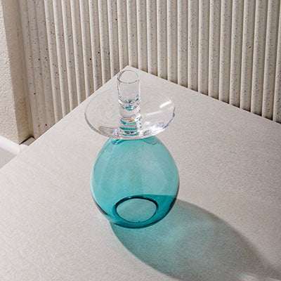 Princess Samdan Turquoise candle holder on a table, featuring a striking turquoise hue with a clear glass top.