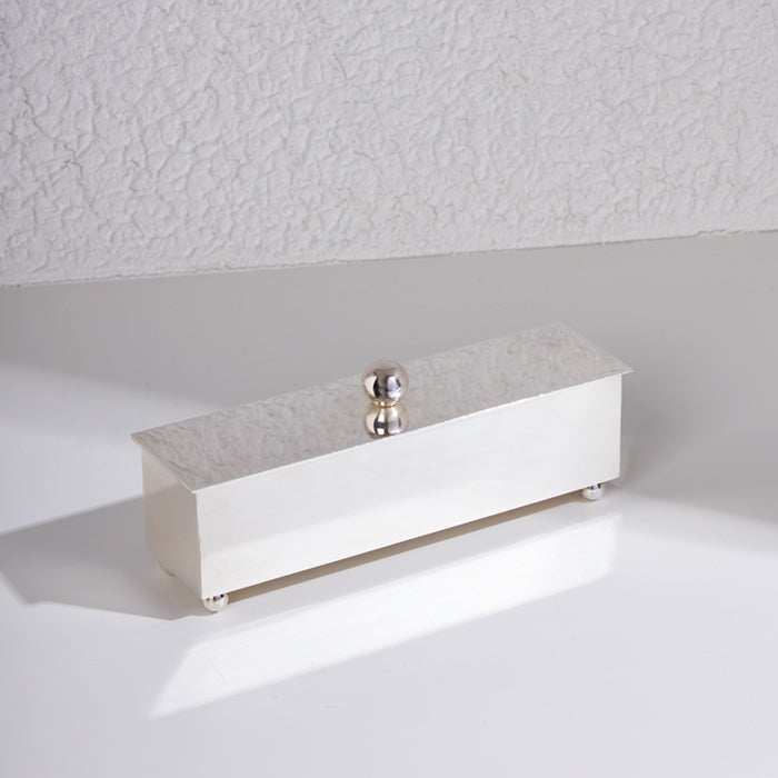 Silver storage box with slanted lid and spherical handle, sleek and minimalist design for luxury home or office use.