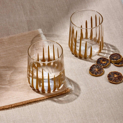 GLORY WATER GLASS with contemporary design and gold accents on a table.