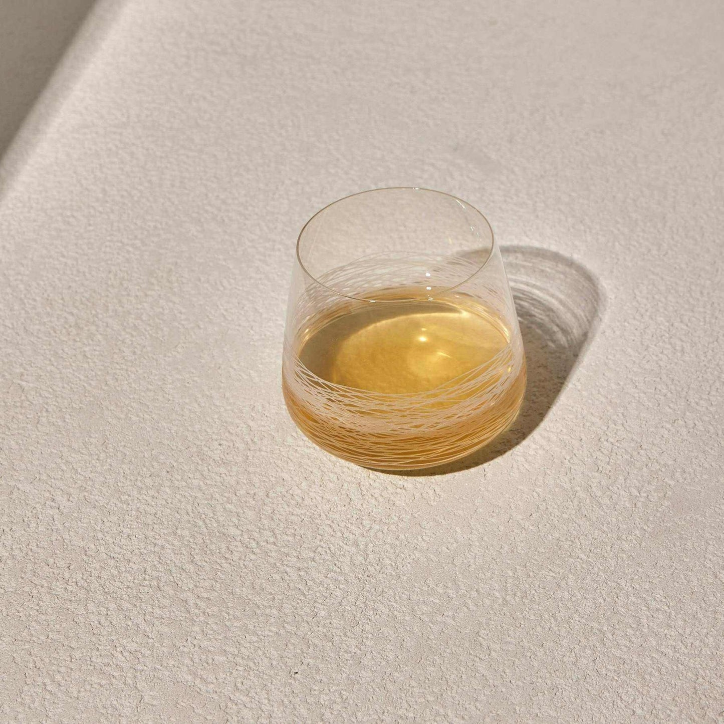 Whiskey glass with deep red band and modern design on a textured surface.