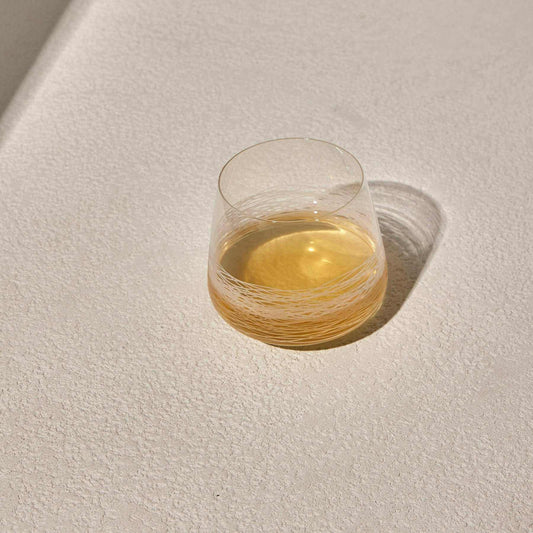 Whiskey glass with deep red band and modern design on a textured surface.