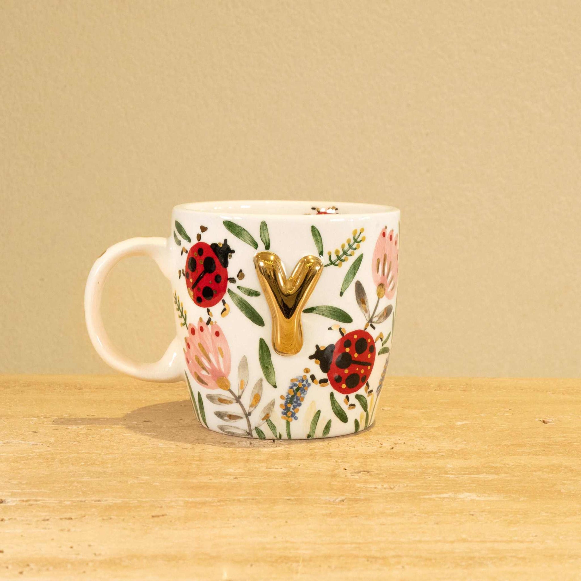 Personalized handmade ceramic mug with gold-plated letter "Y" and floral design.