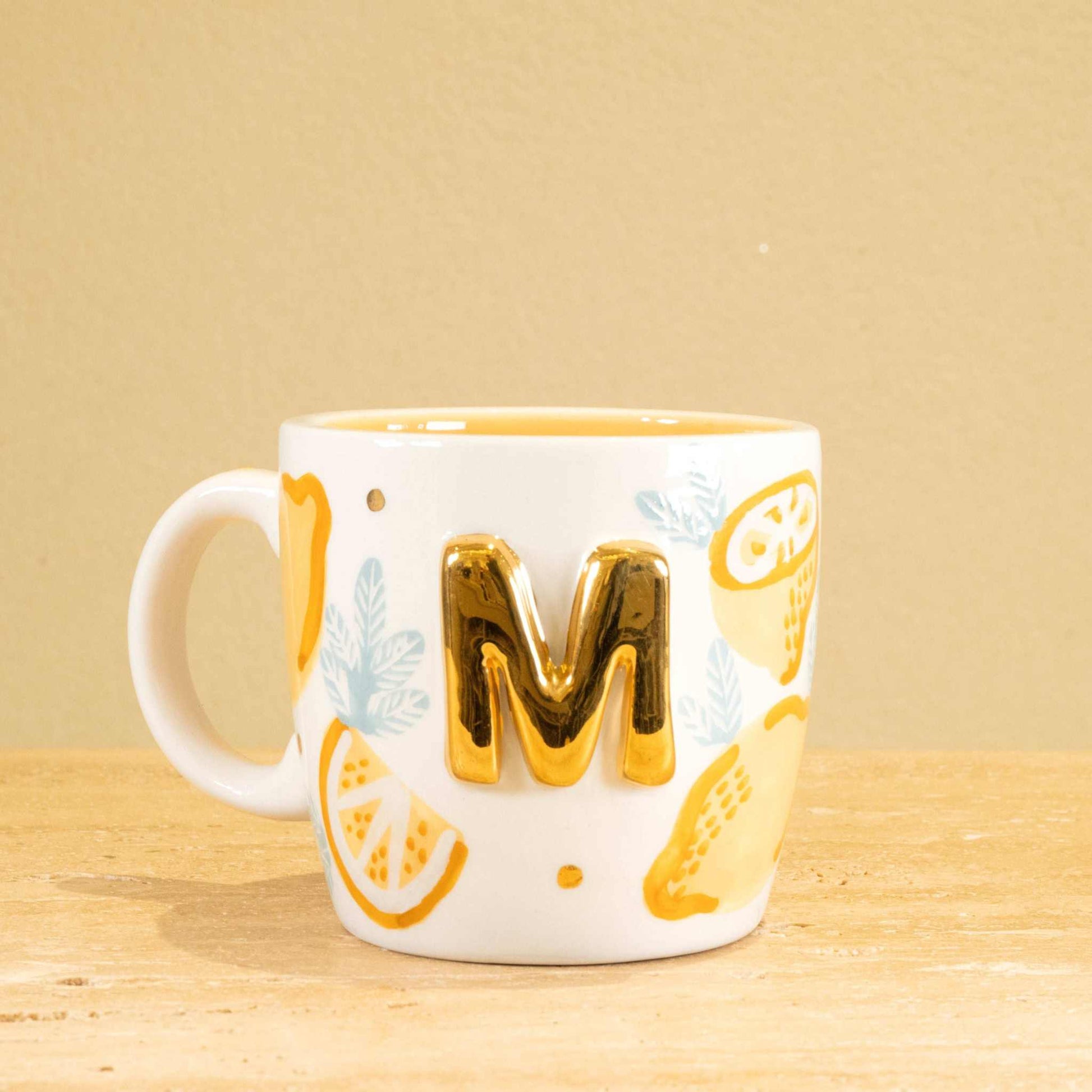 Personalized handmade ceramic mug with gold-plated letter "M" and unique floral design.