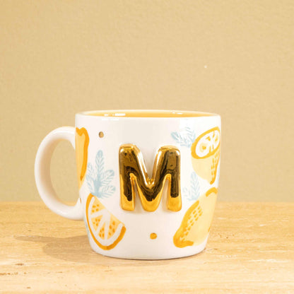 Personalized handmade ceramic mug with gold-plated letter "M" and unique floral design.
