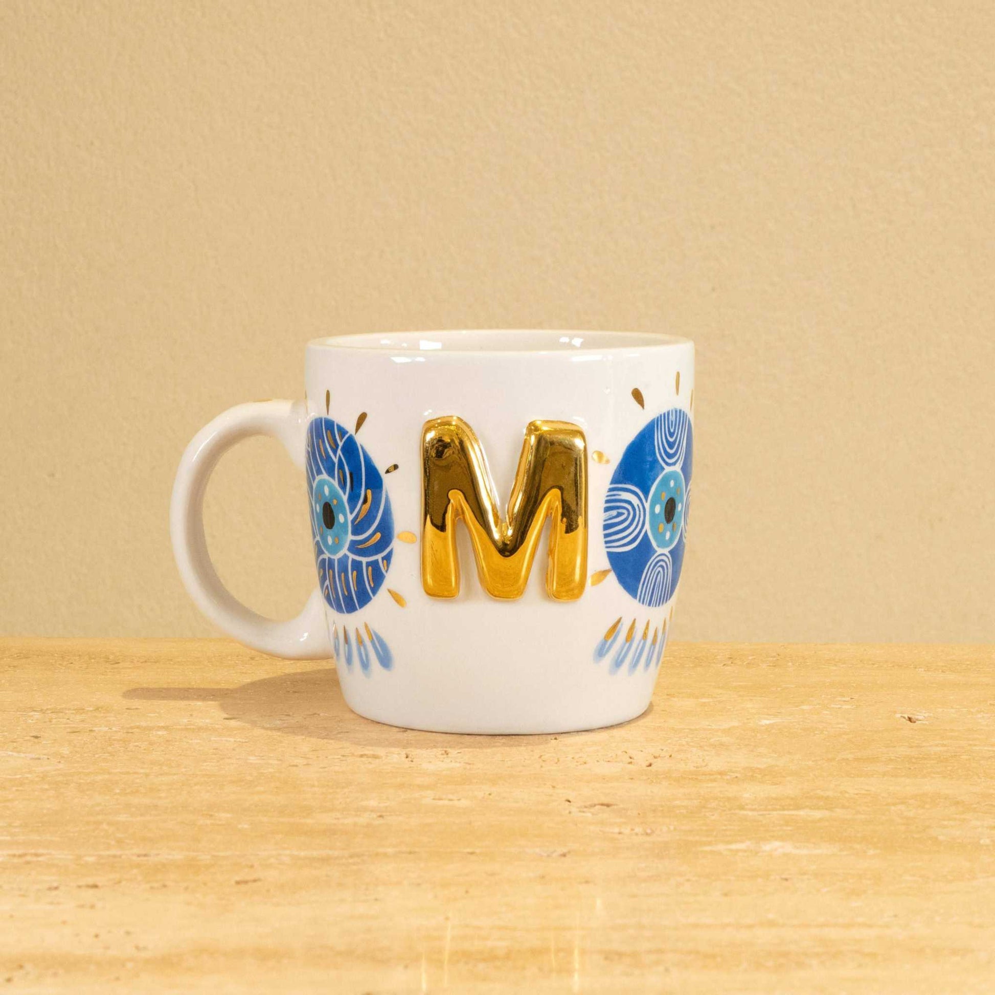 Personalized handmade ceramic mug with gold-plated letter "M" and unique floral design.