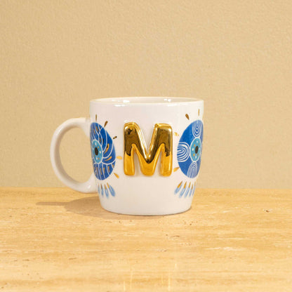 Personalized handmade ceramic mug with gold-plated letter "M" and unique floral design.