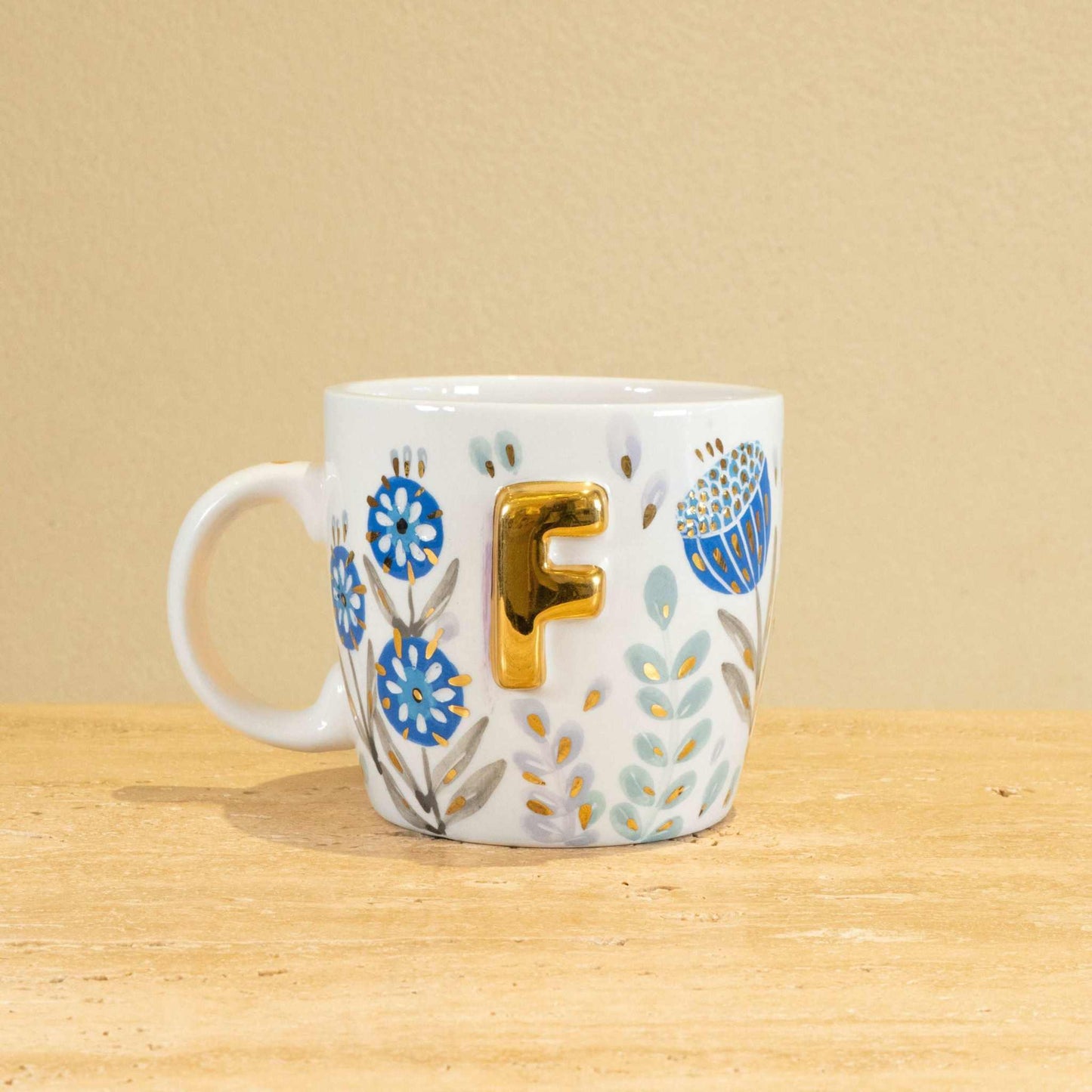 Personalized handmade ceramic mug with gold-plated letter F and floral design.