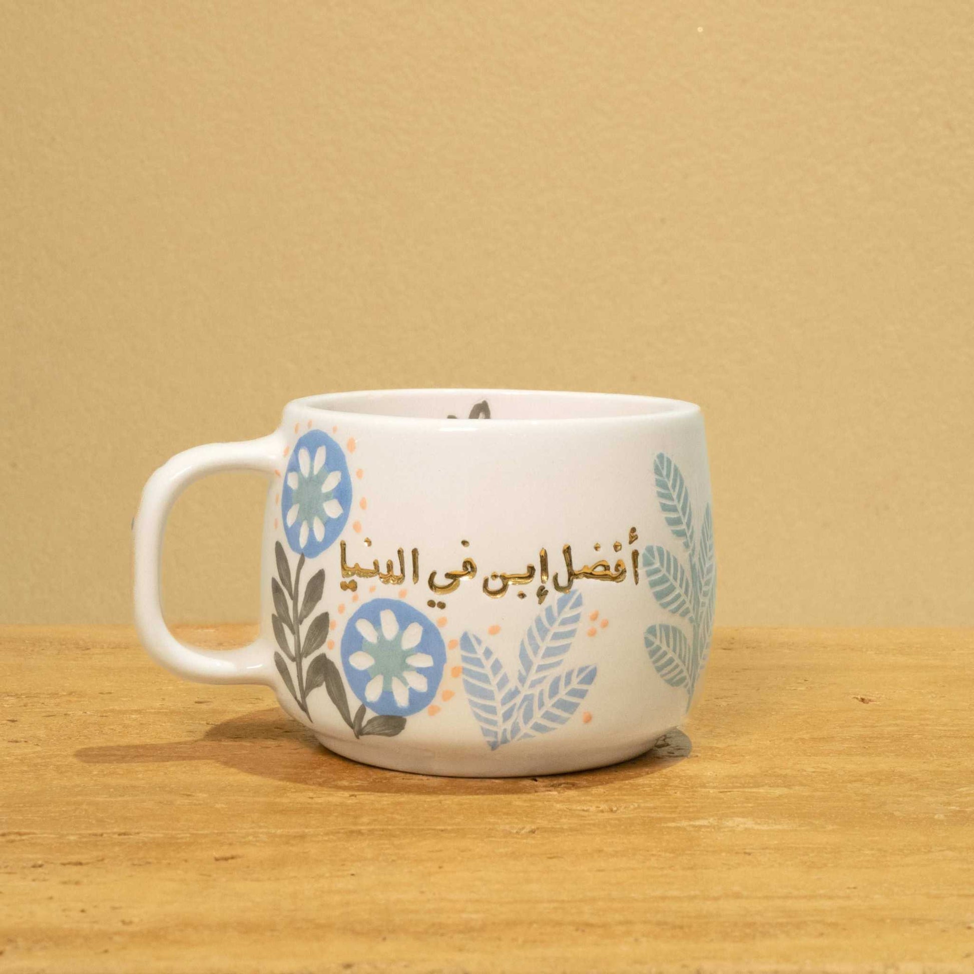 Personalized ceramic mug with gold "Best Son in the World" monogram and floral design.