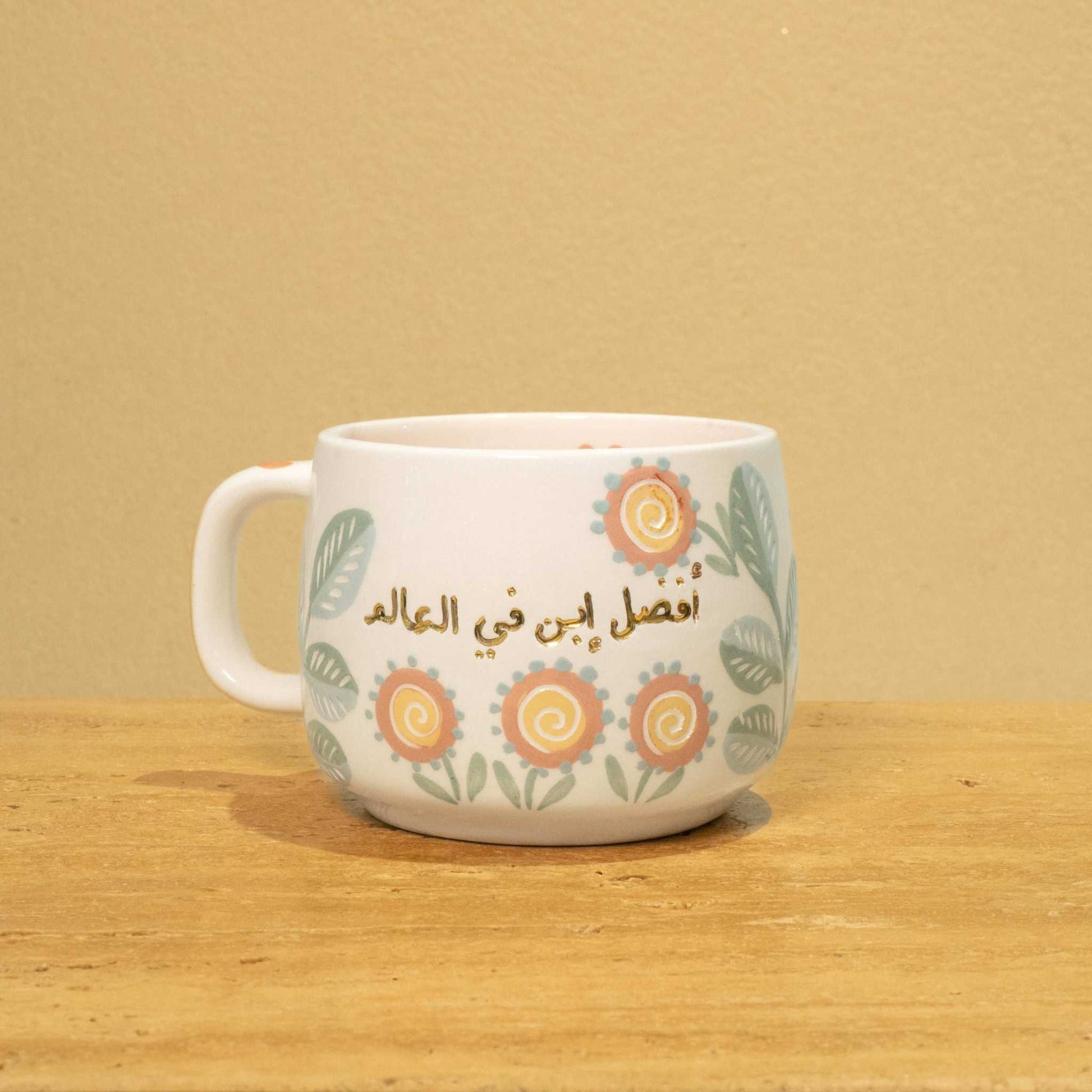 Personalized gold Arabic monogram ceramic mug with "Best Son in the World" and floral design.