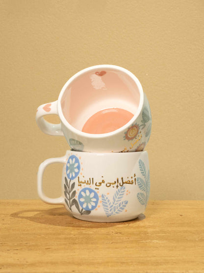 Handmade ceramic mug with gold-plated Arabic text "Best Son in the World" and floral design.