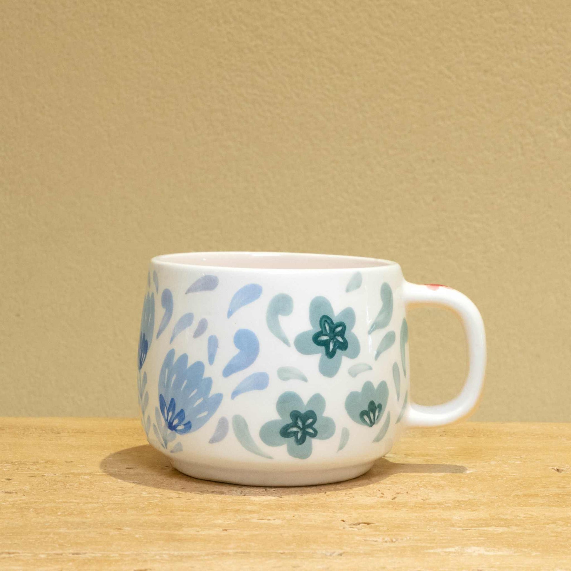 Personalized gold monogram ceramic mug with floral design.