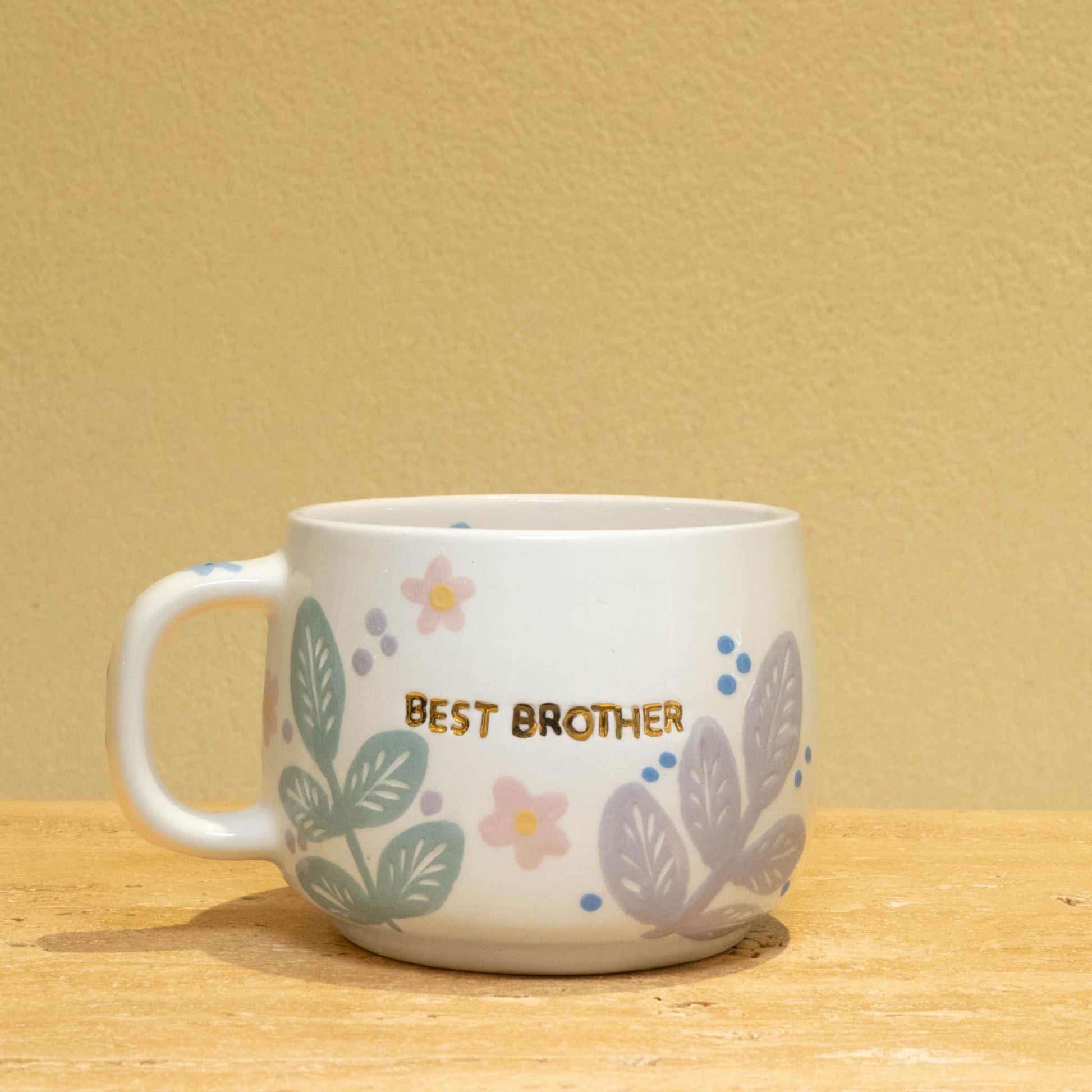 Personalized gold monogram ceramic mug with "Best Brother" and floral design.