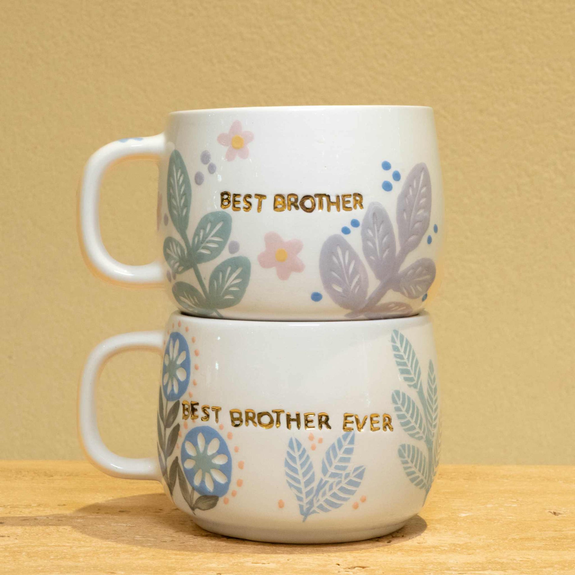 Personalized gold monogram ceramic mug with floral design and "Best Brother" lettering.