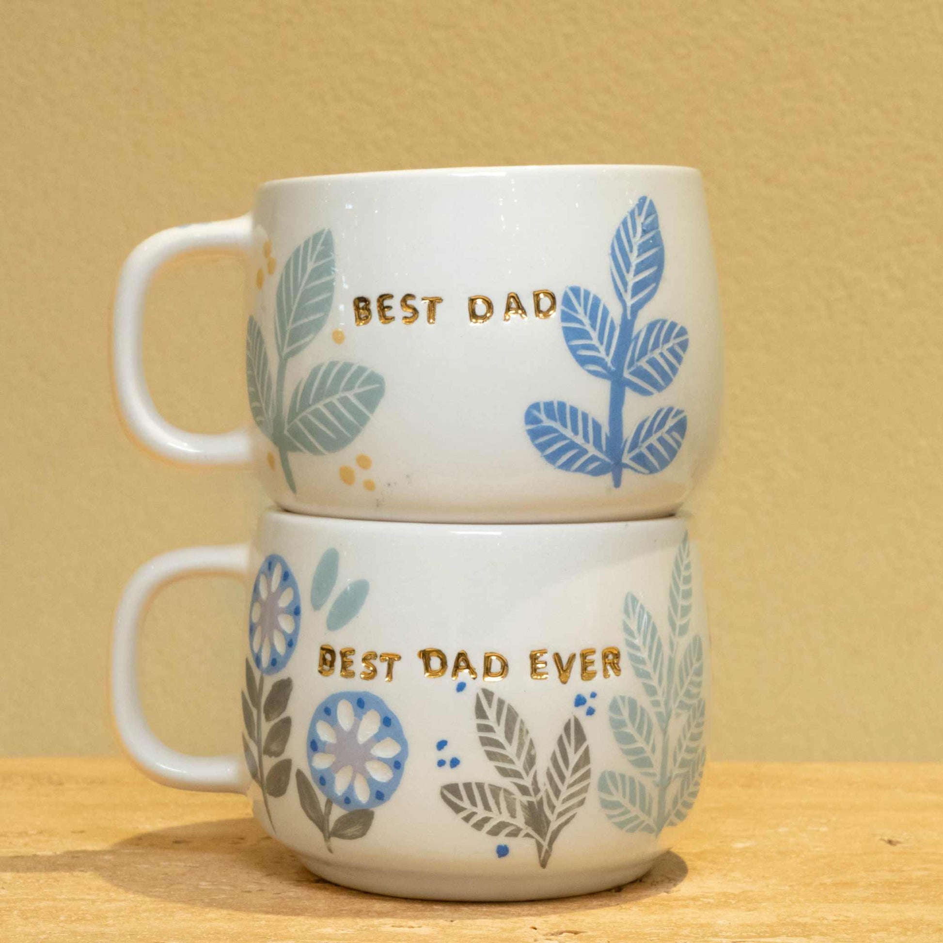 Personalized ceramic mug with gold "BEST DAD" monogram and floral design.