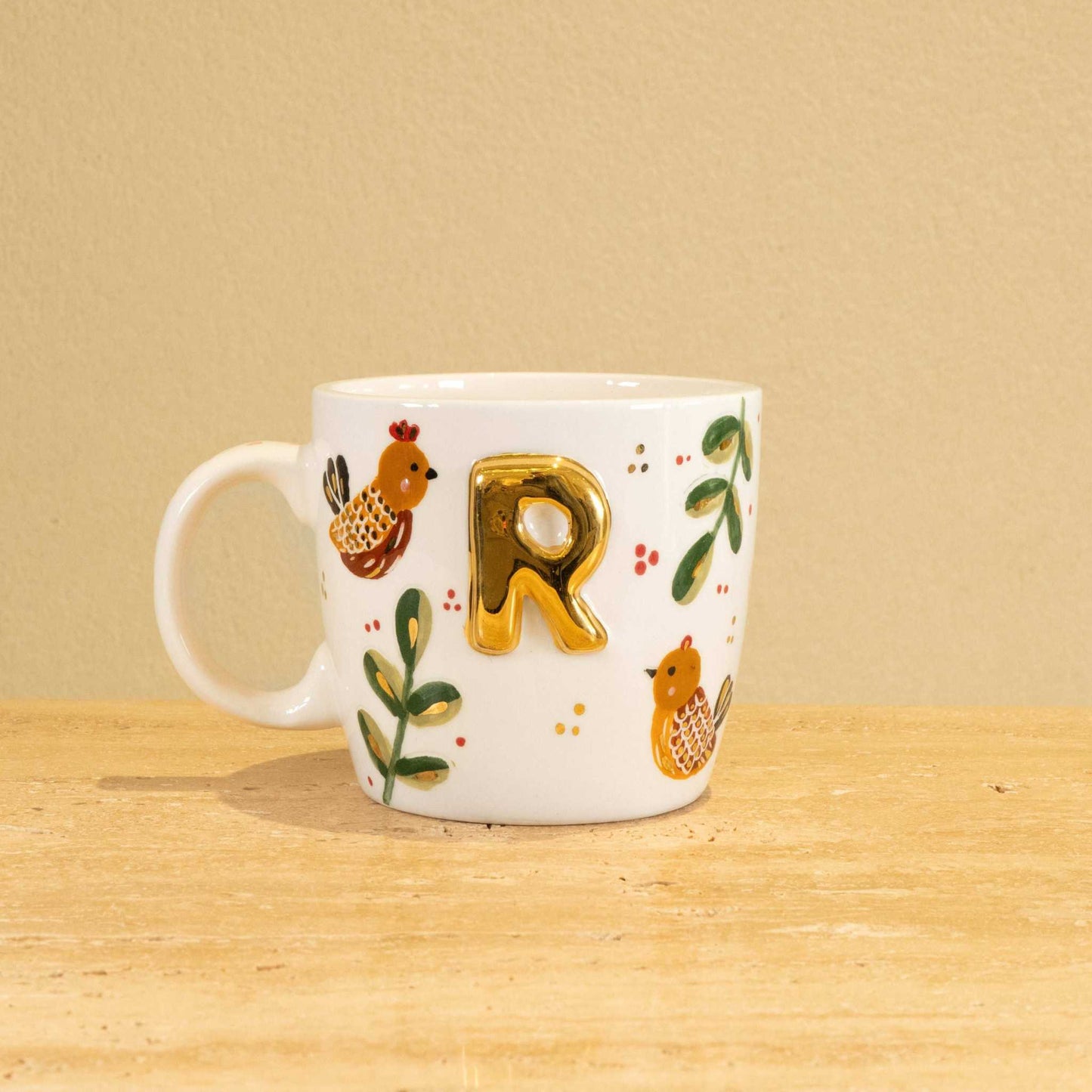 Custom handmade ceramic mug with gold-plated initial "R" and floral design.