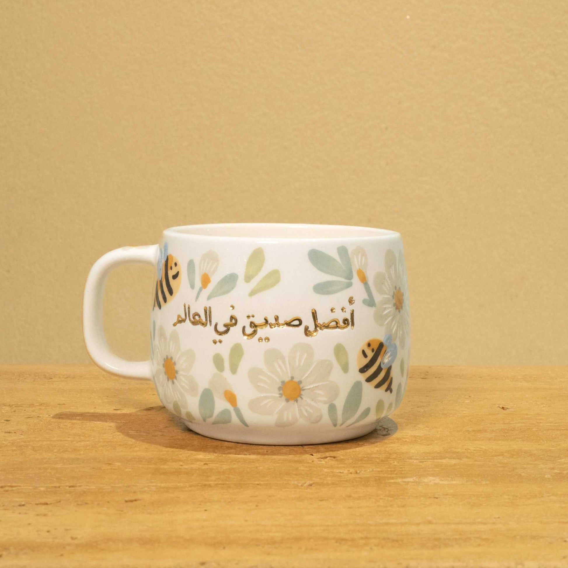 Personalized gold Arabic monogram ceramic mug with "Best Male Friend" text and floral design.