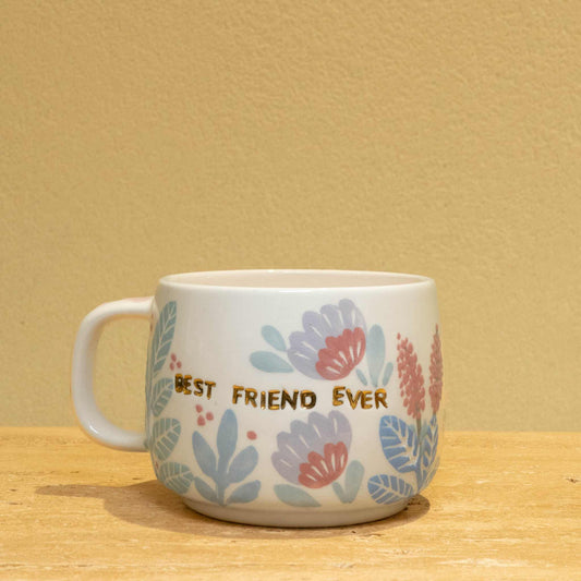 Handmade ceramic mug with gold "BEST FRIEND EVER" lettering and vibrant floral design.