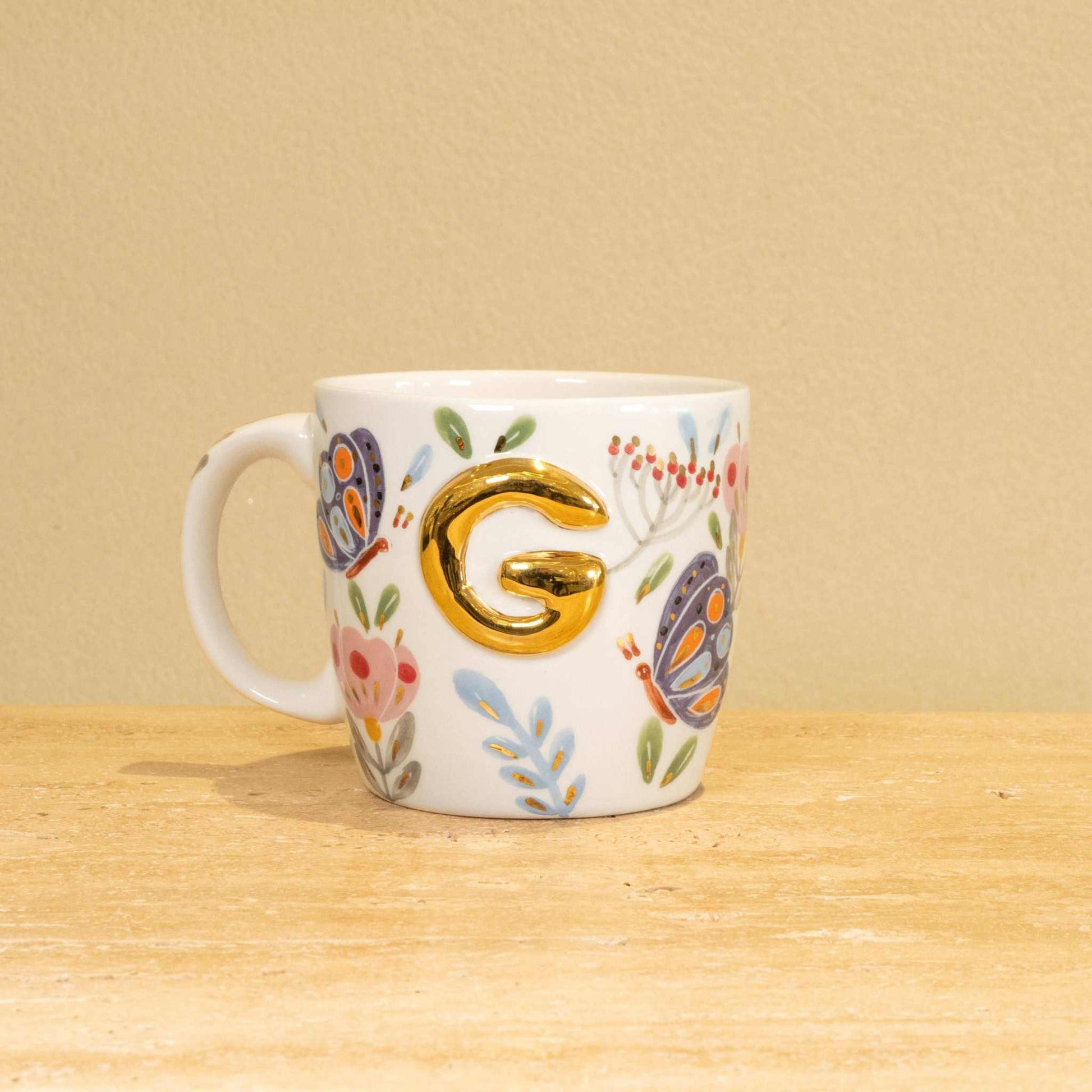 Custom handmade ceramic mug with gold-plated initial "G" and floral design.