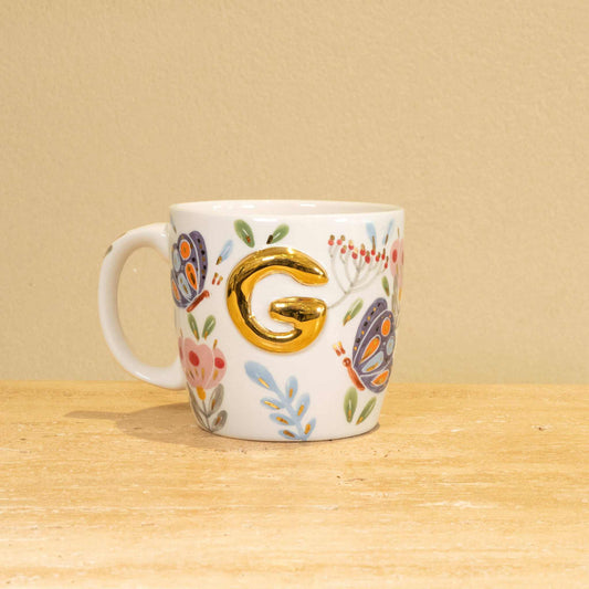 Custom handmade ceramic mug with gold-plated initial "G" and floral design.