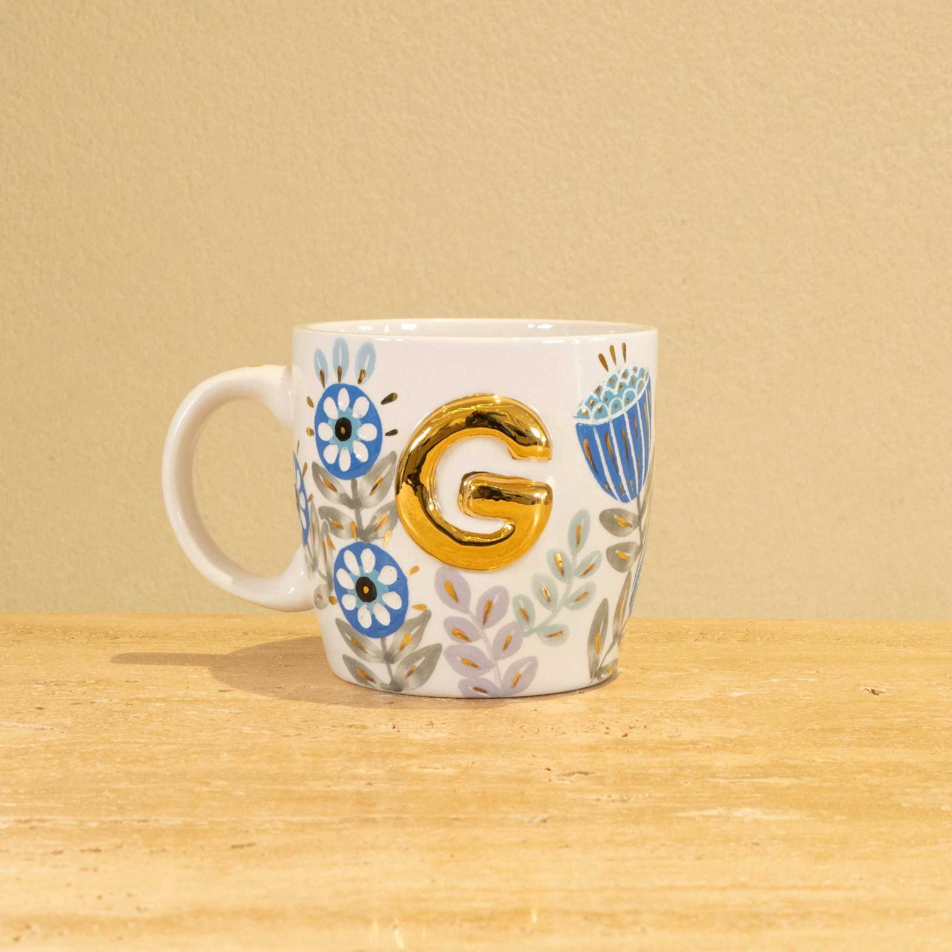 Custom handmade ceramic mug with gold-plated initial "G" and floral design.