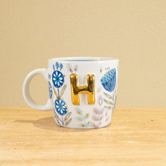 Custom handmade ceramic mug with gold-plated initial "H" and unique floral design.