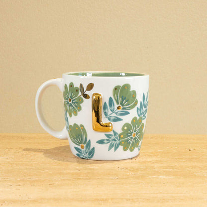 Custom handmade ceramic mug with gold-plated initial "L" and floral design.