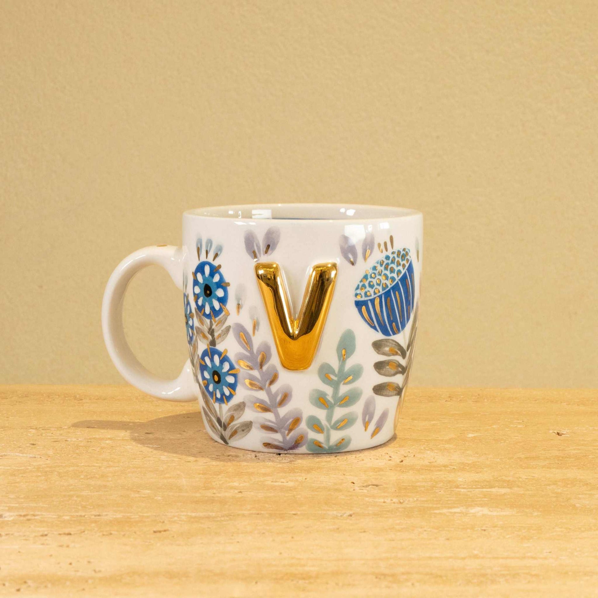 Custom handmade ceramic mug with gold-plated initial "V" and floral design.