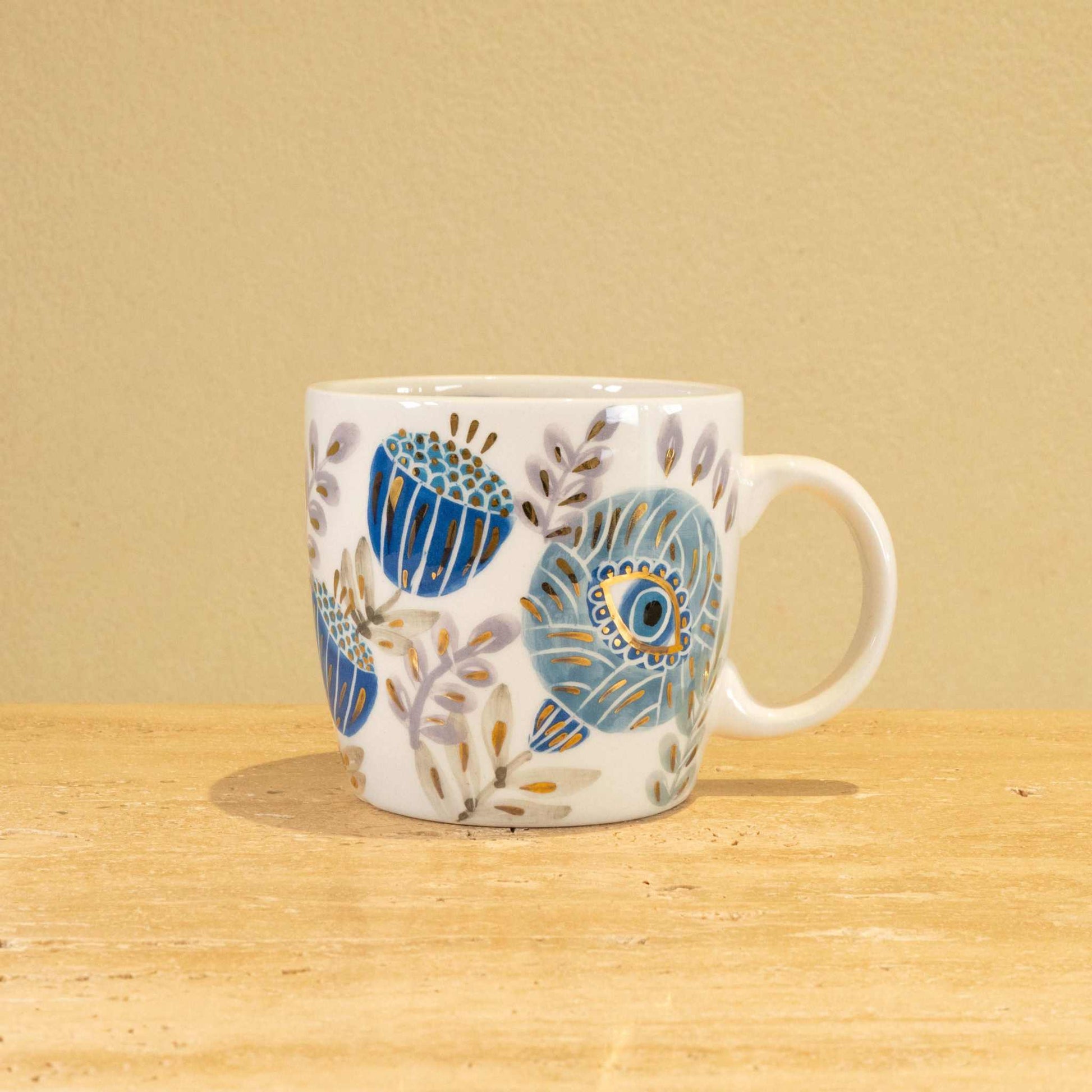 Handmade ceramic mug with gold-plated initial V and intricate floral design.