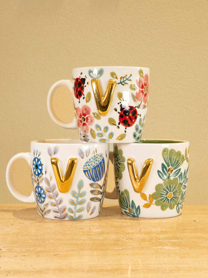 Custom handmade ceramic mug with gold-plated initial "V" and unique floral design.